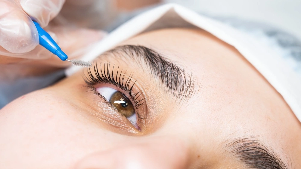 The master combs the eyelashes of the client after the lamination procedure.